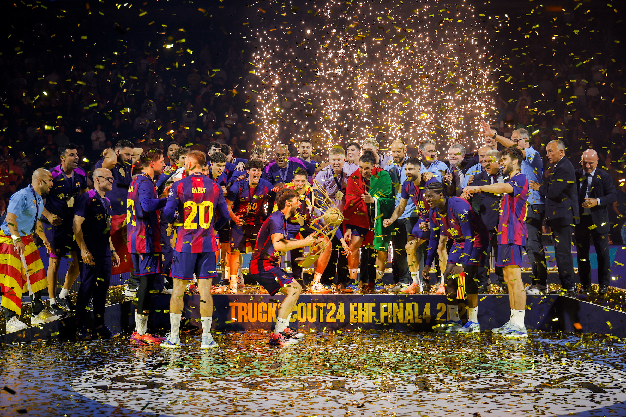 A basketball team celebrates on a podium with confetti and fireworks as they hold a trophy.