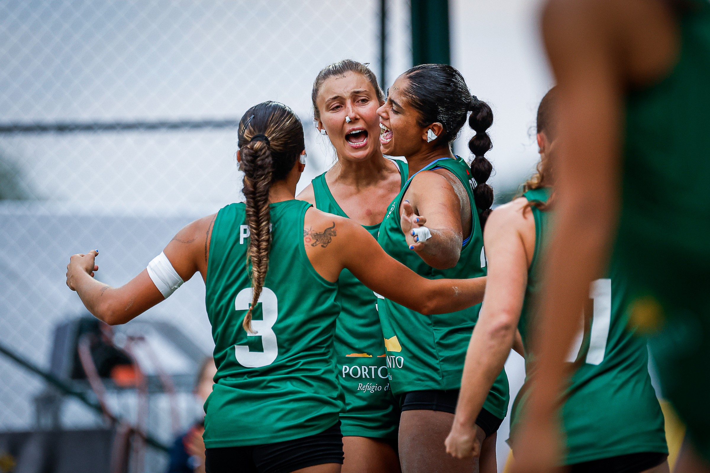 A group of athletes in green jerseys celebrate enthusiastically on a sports field.