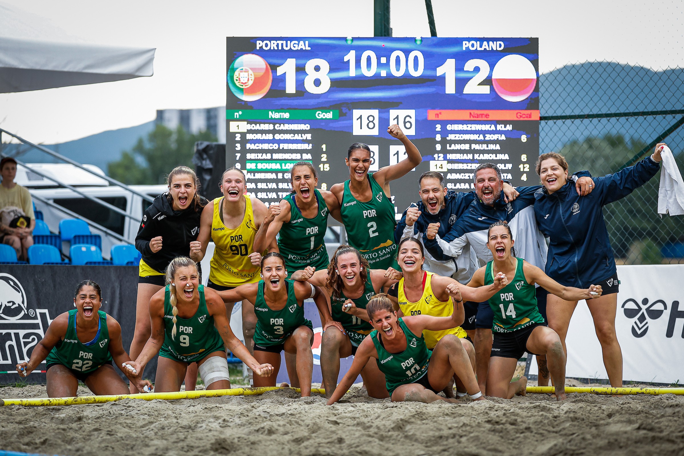 A beach volleyball team in green uniforms celebrates a victory over Poland on the sand, with a scoreboard showing Portugal 18, Poland 12 behind them.