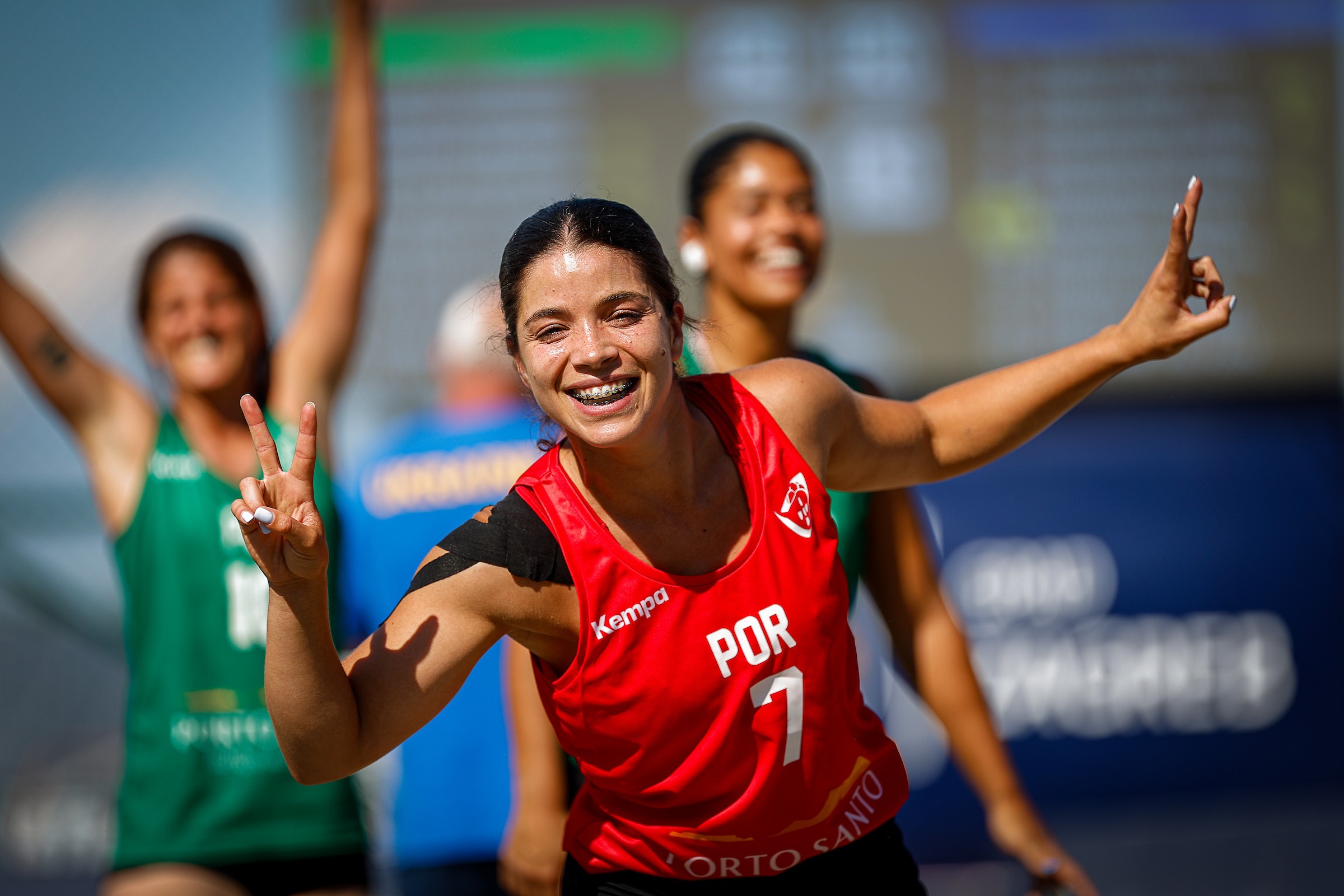 A smiling athlete in a red jersey with "POR" and the number 1 makes peace signs while celebrating on a sports court.