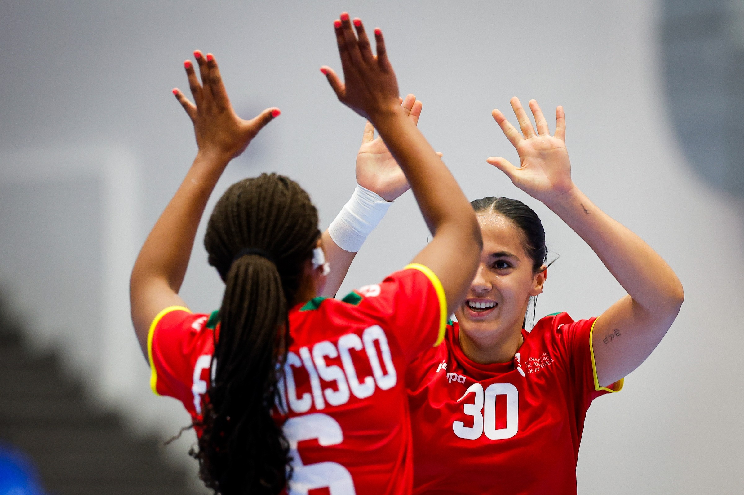 Two athletes in red jerseys celebrate with raised hands, one smiling broadly while the other's back is turned, showing the name "FRANCISCO" and number 6.