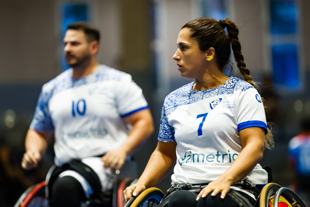 Two athletes in wheelchairs, wearing numbered jerseys, are focused during a competitive event.